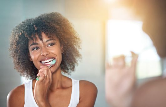 brossage des dents d'une jeune femme se brossant les dents dans la salle de bains.