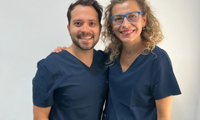 Dentiste français a l'étranger souriant tenant des instruments dentaires et une brosse à dents, prêt pour un examen oral.