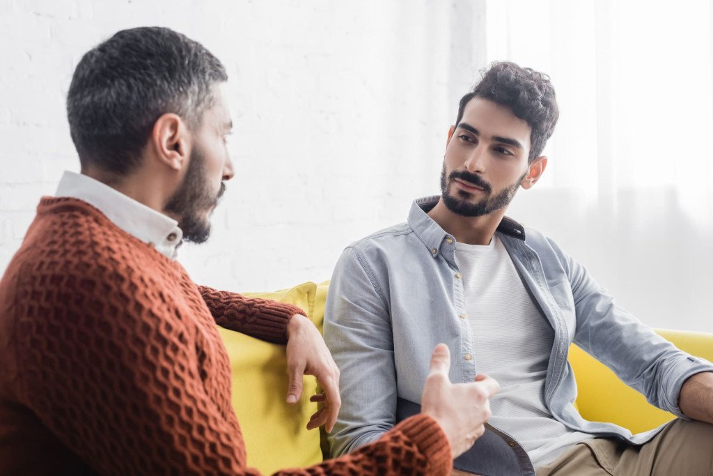 Deux hommes discutant sérieusement, l'un des deux semble attentif aux paroles de l'autre, illustrant une conversation honnête sur la mauvaise haleine.