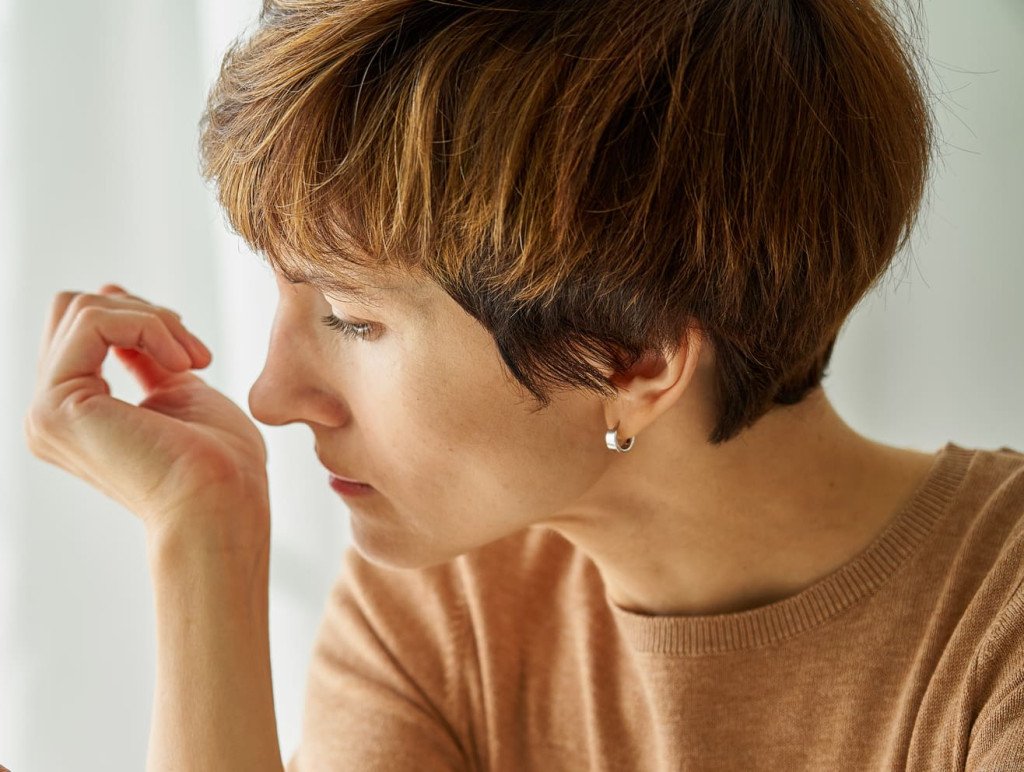 Une femme vérifie son haleine en sentant son poignet, illustrant une méthode simple pour évaluer la mauvaise haleine.