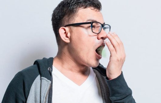 Un homme se couvre la bouche avec la main, illustrant le problème de la mauvaise haleine.