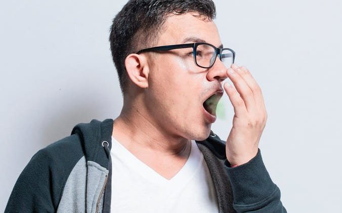 Un homme se couvre la bouche avec la main, illustrant le problème de la mauvaise haleine.